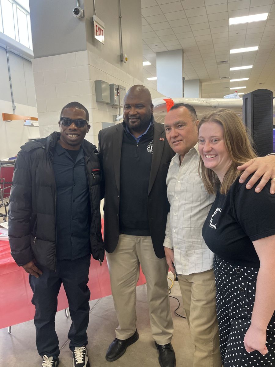Jamel Miller with three community partners at an indoor community event