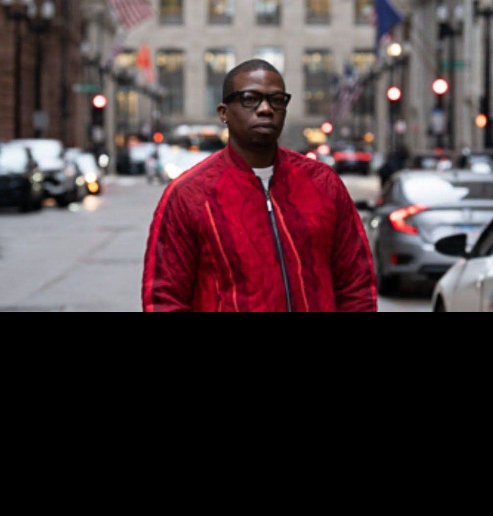 Jamel Miller in a red jacket standing on a downtown Chicago street
